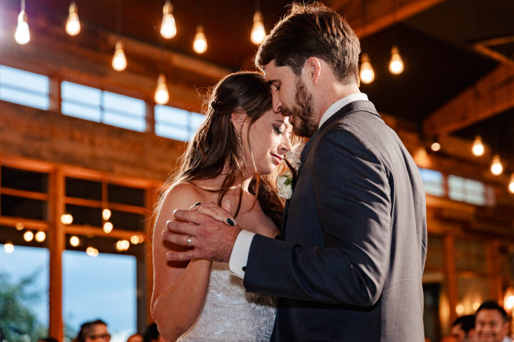 bride and groom share their first dance under the warm garden lights during their wedding reception